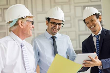 97351123-three-engineers-looking-at-tablet-and-laughing